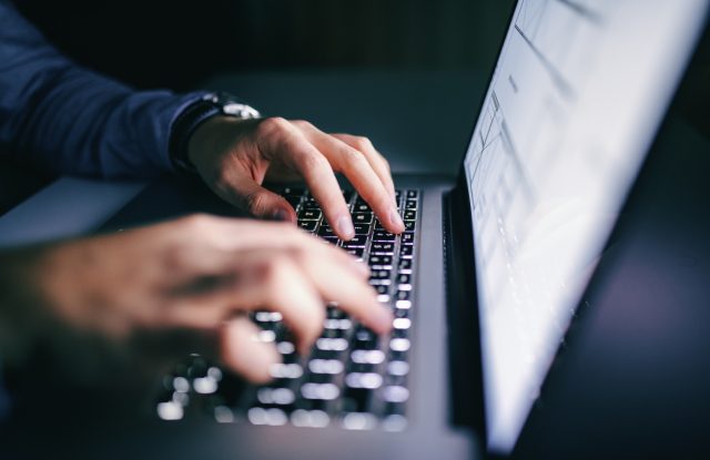 Close up of hands typing on laptop. Night work concept.