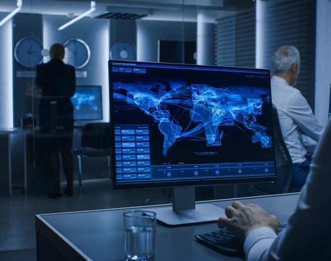Back View of the Cyber Security Officer Working on Personal Computer Showing Traffic Data Flow in the System Control Room full of Special Intelligence Agents.