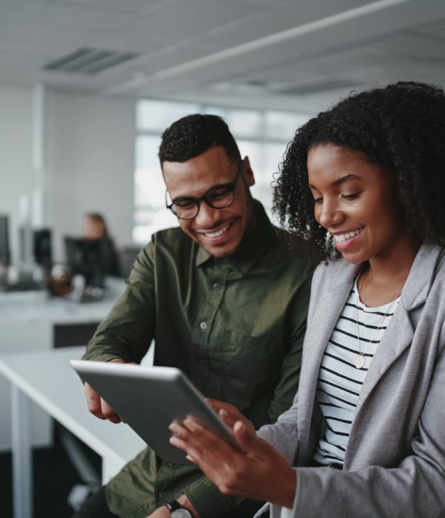 Professional young businesspeople using tablet computer smiling in office