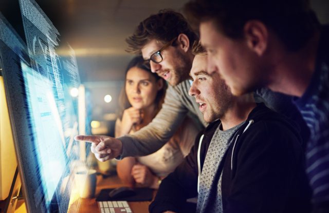 Shot of a group of programmers working on a computer code at night